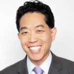 A professional headshot of Steve Chee wearing a grey suit and a patterned lavender tie.
